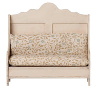 The Maileg Kitchen Bench, Mouse - Light Sand by Maileg features a cream-colored wooden frame with decorative backrest and armrests. It comes with a beige cushion adorned with a subtle leaf and berry pattern in muted tones, giving it a rustic, vintage charm—perfectly sized for Maileg mice to enjoy their miniature meals in style.