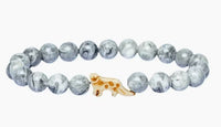The Ascent - Alpine Snow Leopard bracelet by fahlo features gray and white marbled beads with a gold leopard charm—a stylish accessory that supports wildlife conservation.
