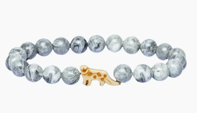 The Ascent - Alpine Snow Leopard bracelet by fahlo features gray and white marbled beads with a gold leopard charm—a stylish accessory that supports wildlife conservation.