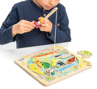 A child plays Pond Dipping by Tenderleaf, using a magnetic fishing rod to catch colorful wooden pond creatures from a pond-themed play set.