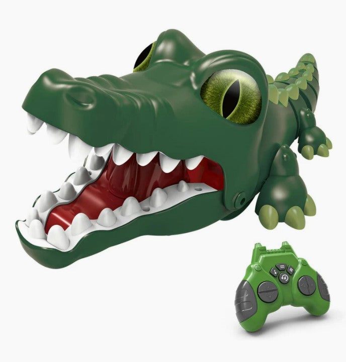 The Crazy Croc R/C by Jupiter Creations, Inc is a playful, green remote-controlled crocodile toy featuring a cartoonish design with big eyes, an open mouth displaying white teeth and a red tongue. A matching green remote with black buttons accompanies this fun RC vehicle.