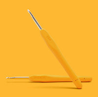 Two yellow ergonomic crochet hooks from The Woobles’ Sam the Sloth Crochet Kit are displayed on a yellow background. One hook is flat and the other leans, with "WOBBLES" and "4MM" visible on their handles.