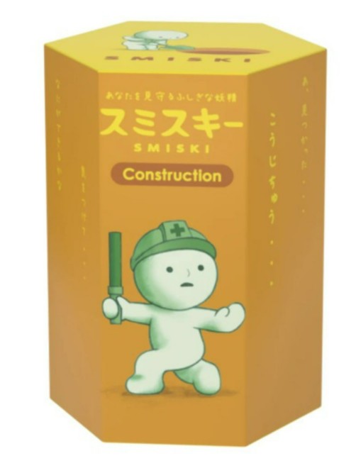 A hexagonal yellow box from Dreams USA features a small green character wearing a construction helmet and holding a baton. This glow-in-the-dark Smiski Construction Series box includes Japanese text above and on the sides, making it a fun collectible blind-box figurine for fans.