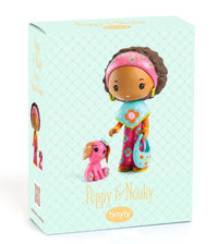 The DJECO Tinyly Poppy & Nouky collectible figure set by DJECO features a doll with brown skin, curly hair, colorful clothes, a headband, and a blue purse, standing next to her small pink dog—perfect for imaginative play.