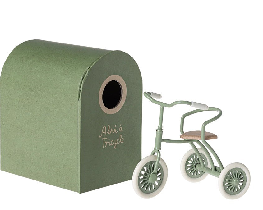 A small green Maileg Tricycle Garage, featuring a circular opening and “Abri à Tricycle” text, is perfect for miniature storage or organizing Maileg mouse accessories.