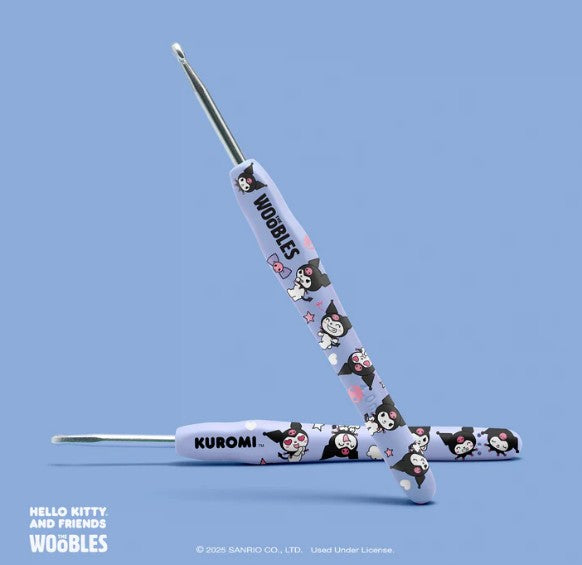 Two Kuromi crochet hooks from The Woobles Kuromi Crochet Kit feature playful illustrations, hearts, and stars on a light purple background. Displayed on a solid light blue surface, they're perfect for any Sanrio fan's collection.