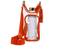 The Wander Full Brand Clear Stadium HydroBag Orange features orange trim, gold zippers, an adjustable orange strap, and a matching pouch. Inside, it includes a reusable water bottle holder with a white water bottle topped with a gold cap.