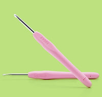 Two pink-handled crochet hooks from The Woobles’ Andre the Skunk Pink Crochet Kit are shown on a light green background. Both feature ergonomic handles and metal tips—perfect for beginner-friendly crochet.