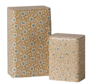 A set of two rectangular Maileg metal boxes with tight-fitting lids, featuring ocher and blue floral designs. This Maileg Metal box set - Flowers - Ocher/Blue (2 pcs) combines style and practicality, with the taller tin placed behind and to the left of the shorter one.
