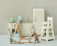 Three stuffed bunny toys in striped outfits play in a vintage miniature kitchen featuring Maileg Mouse furniture, adorable accessories, and the Maileg Bread Box W. Utensils, Miniature by Maileg among items like a fridge, stove, sink, toaster, and white high chair.