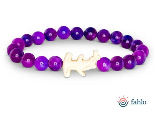 Introducing "Shark Week - Anemone" by fahlo: a beaded bracelet featuring round purple beads and a cream-colored shark-shaped charm, showcased on a white background with the fahlo logo in the bottom right corner. Ideal for marine conservation advocates eager to support shark tracking initiatives.
