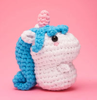 Billy the Unicorn Crochet Kit by The Woobles features a white body, blue mane, pink horn, and black eyes—perfect for inspiring your next unicorn project or for trying a beginner crochet kit.