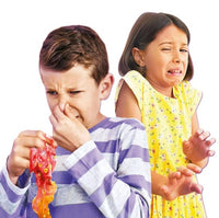 A boy pinches his nose and grimaces while gripping a container of License 2 Play’s So Slime Stinky Slime, as a girl in a yellow dress recoils in disgust.