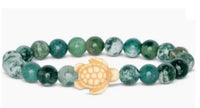 The "Journey - Seagrass Green Sea Turtle" bracelet by fahlo features green marbled beads and a central light turtle charm—ideal for marine conservation enthusiasts.