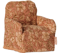 A petite, plush Maileg Folding chair for mice, adorned in a pink and beige floral fabric and featuring softly rounded arms with a gently slanted back—ideal as charming dollhouse furniture or as the perfect seat for your Maileg mouse.