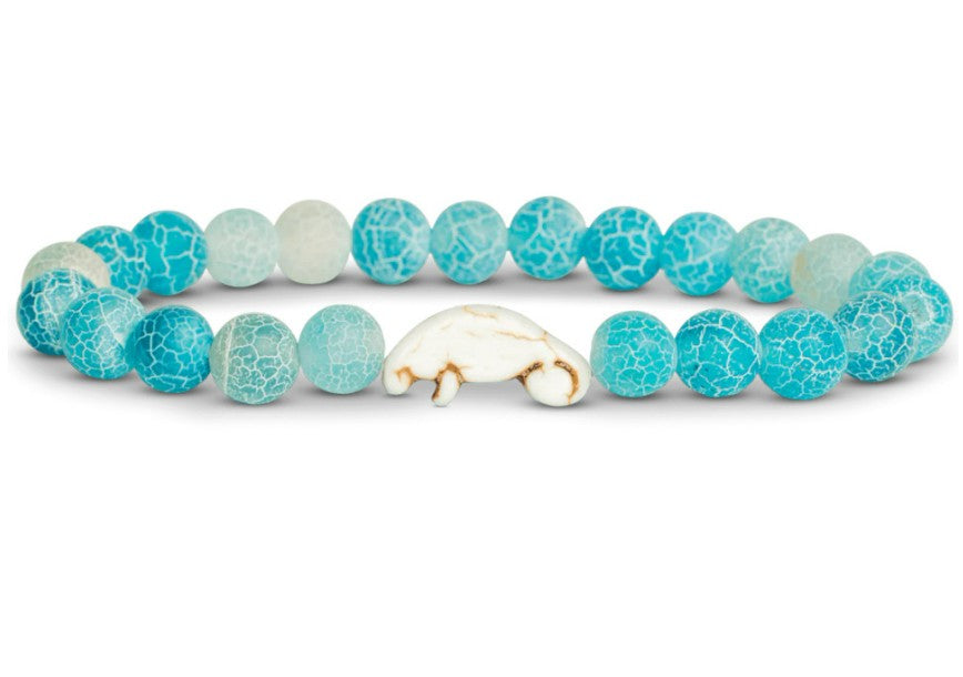 The fahlo Drift - Aqua Blue Manatee bracelet features round crackled turquoise-blue beads and a single white manatee-shaped bead—perfect for wildlife conservation enthusiasts.