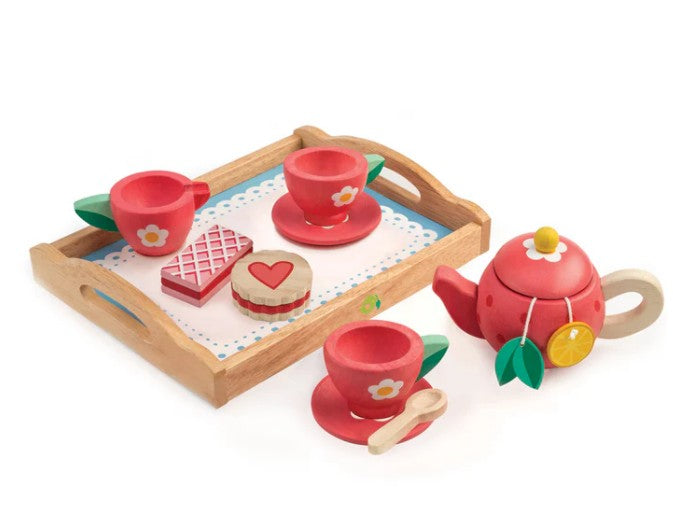 The Tenderleaf Tea Tray Set includes a wooden tray, red teapot, three red teacups with saucers, two toy cookies, and two spoons. With floral and leaf designs, it’s perfect for imaginative play.