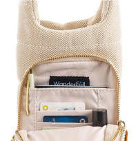 The HydroBag Handle Oatmeal Canvas by Wader Full Brand is a beige fabric bag with a gold zipper, partially open to show cards, a tube, and an interior pocket featuring a tag that reads “WanderFull.” This versatile hydration bag accessory offers an organized interior with sections for various items.