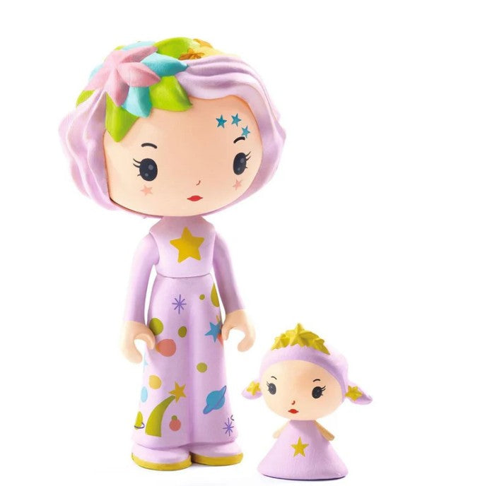 Two pastel-hued Tinyly dolls from the DJECO Tinyly Violet Tinyroom set stand together; the taller doll features a star on her dress and a flower in her hair, while the smaller one wears a yellow crown-like headpiece. Both wear purple outfits decorated with stars and planets, perfect for imaginative play as part of the enchanting DJECO collection.