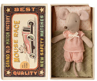 The Maileg Little Sister Mouse In Matchbox by Maileg features a mouse in a pink outfit lying in a cozy matchbox bed with a polka-dot pillow and green blanket, beside a vintage-style Best Quality Mouse Race box.
