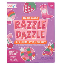 Front of an Ooly Mini Razzle Dazzle: D.I.Y. Gem Sticker Kit - Magic box in pink, featuring vibrant gem art designs, a list of included contents, and a small parts warning label. Ideal for crafting magical-themed creations. Recommended for ages 6 and up.