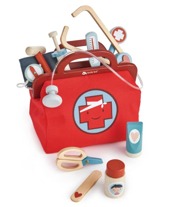 The Tenderleaf Doctors Bag is a child-sized play set featuring a red wooden doctor’s bag with a smiling medical cross, complete with wooden medical tools like a stethoscope, thermometer, syringe, scissors, ointment, and medicine bottle.