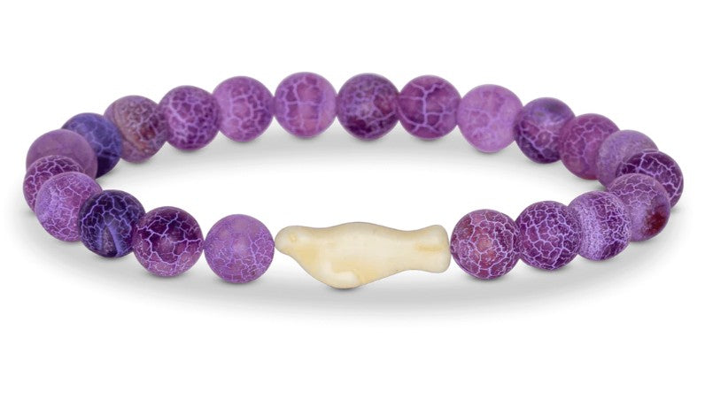 The fahlo "Glide - Coral Reef Violet Seal" bracelet features round, crackled purple beads and a central cream-colored seal bead—ideal for wildlife tracking fans.