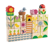 Tenderleaf Garden Blocks are stacked to create a playful garden scene with flowers, birds, a ladybug, and nature patterns. Some wooden blocks feature carrots, leaves, and geometric designs for imaginative play.