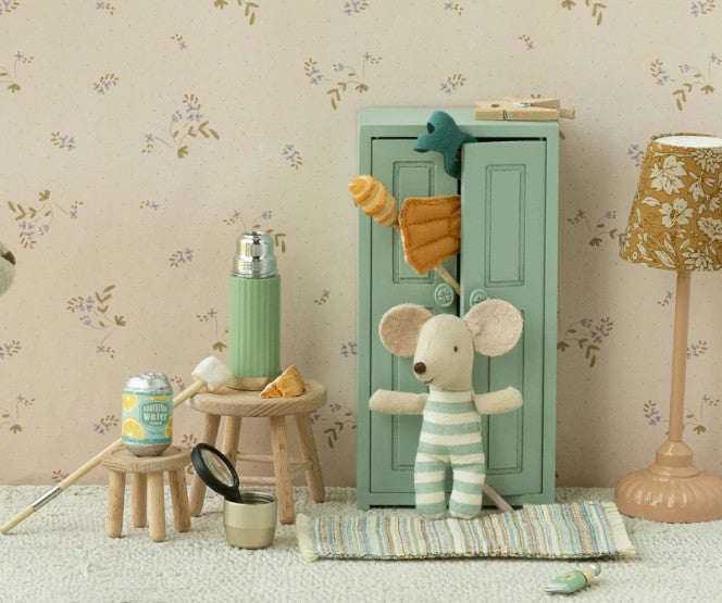 A small toy mouse in striped pajamas stands by a mint locker, surrounded by stools with miniature food and the Maileg Thermos And Cups, Mouse - Mint. This charming Maileg scene inspires imaginative dollhouse play.