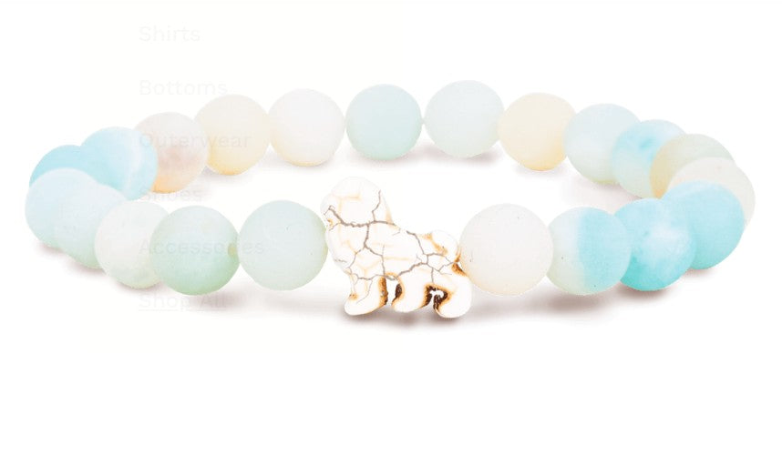 The Excursion - Sky Stone Lion bracelet by fahlo features pastel blue and white beads with a white and gold marbled lion charm, inspired by animal tracking for wildlife conservation.