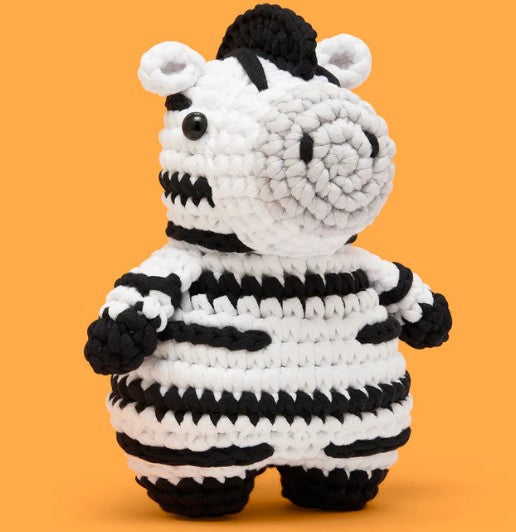 Jasper the Zebra Crochet Kit by The Woobles features a charming black-and-white striped zebra made of yarn, with small black eyes and a round snout—ideal as a beginner-friendly crochet project or thoughtful gift.