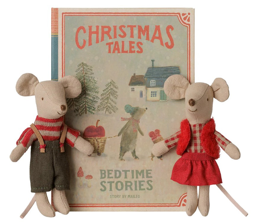 Two Maileg Christmas twin mice—Little Sister and Brother—dressed in festive outfits, sit in front of a Maileg children’s book titled “Christmas Tales: Bedtime Stories.” The charming cover features another mouse along with trees, a house, and snowy scenery—making these Maileg Christmas mice from the beloved brand the perfect holiday gift for young readers.