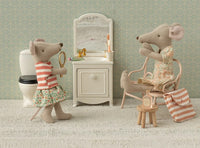 Two Maileg mice are in a dollhouse bathroom with Maileg mouse accessories. One brushes its teeth with the Maileg Toothbrush Set In Bag, Mouse - Coral Stripe, while the other stands holding a mirror for charming pretend play.