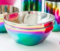The ahimsa Rainbow Smart Snacking Bowl (12 oz) is a BPA-free stainless steel bowl with a shiny iridescent rainbow finish, reflecting vibrant colors like pink, blue, green, and yellow.