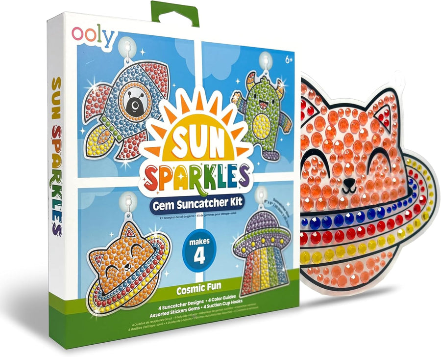 The Ooly Sun Sparkles: Gem Suncatcher Kit – Cosmic Fun features a vibrant box decorated with designs of a rocket, alien, UFO, and cat. This enjoyable craft kit comes with one finished orange cat suncatcher adorned with sparkling gems and beads, making it perfect for creating celestial or space-themed window art. Suitable for ages 6 and up.