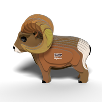 A 3D layered cardboard model of a bighorn sheep with large curved horns and distinctive white and brown markings, featuring the words "EUGY Bighorn" on its side, stands on a white surface. The EUGY Bighorn 3D Puzzle by Eugy is an eco-friendly toy that serves as both an educational STEM craft and a sustainable 3D puzzle.