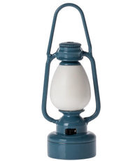 The Maileg Vintage Lantern, Mouse - Blue by Maileg features a blue vintage style with a white frosted glass center, metal handle, and base switch—perfect as a charming camping accessory or playful miniature lantern.