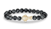 The fahlo Quest - Ocelli Stone Whale Shark bracelet features black and gray speckled beads and a beige, spotted whale shark centerpiece—an ideal accessory for marine conservation enthusiasts.