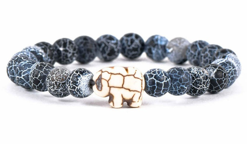 The fahlo Expedition - River Blue Elephant bracelet features dark blue and white crackle-pattern beads with a white elephant-shaped centerpiece—a stylish way to support elephant conservation.