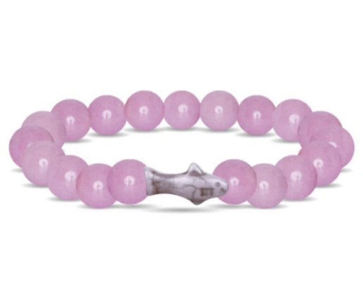 The Voyage - Lilac Glow Shark bracelet by fahlo features round, light pink beads and a small silver shark charm—ideal for unique jewelry lovers and those who support shark conservation.