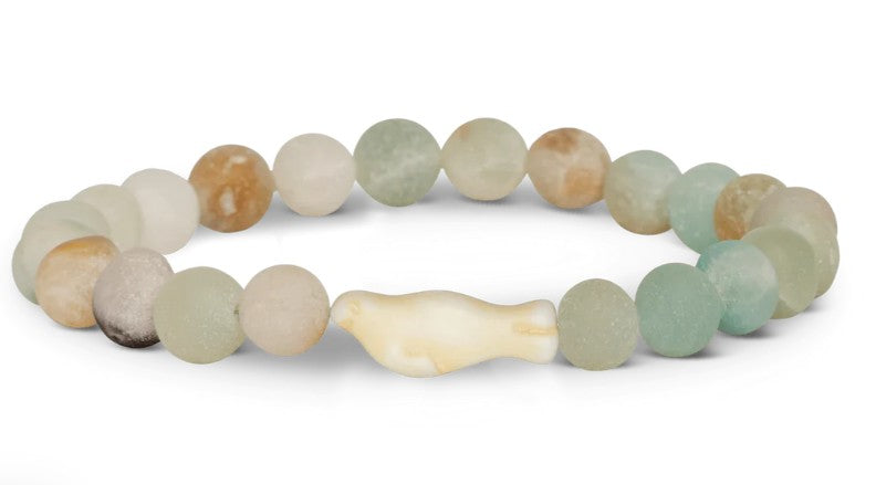 The fahlo Glide - Sky Stone Seal is a wildlife conservation bracelet with round, frosted green, tan, and white beads, featuring a white seal-shaped bead at the center.
