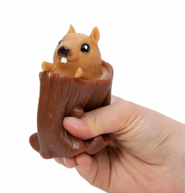 A hand squeezes the Schylling Toys Nutty Squirrel Popper, a toy shaped like a brown tree trunk with an adorable squirrel face popping out of the top—making it the perfect fidget toy for stress relief and fun.