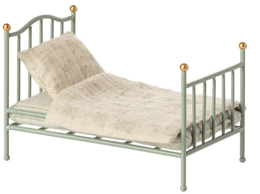 The Maileg Vintage Single Bed, Mouse - Mint by Maileg is a small, light green miniature bed with gold finials, a cream patterned quilt and pillow—perfect for dolls or miniature settings with its classic vintage design.