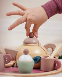 A child lifts the lid of the Tenderleaf Birdie Afternoon Tea Stand, surrounded by pastel toy cups, spoon, and tea set pieces—perfect for imaginative pretend tea parties.