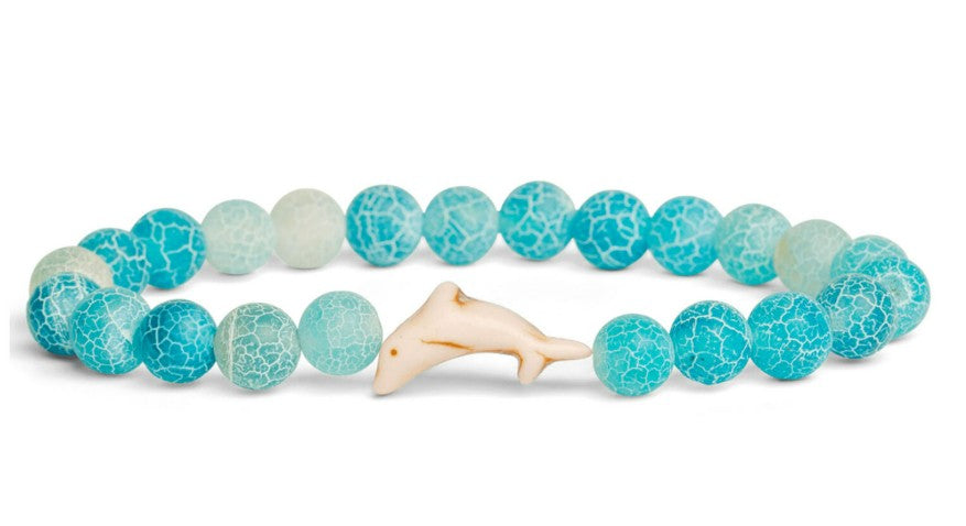The fahlo Odyssey - Aqua Blue Dolphin bracelet features crackled light blue and turquoise beads with a white dolphin charm—perfect for marine conservation enthusiasts.