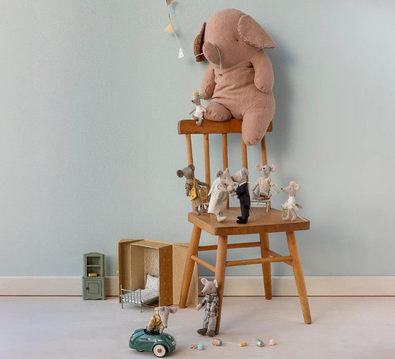 A large stuffed elephant sits on a wooden chair, surrounded by small toy mice—including the Maileg Wedding Mice Couple In Box, Mum And Dad from Maileg—with miniature furniture, a keepsake box, and a toy car nearby against a light blue wall.