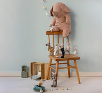 A large stuffed elephant sits on a wooden chair, surrounded by small toy mice—including the Maileg Wedding Mice Couple In Box, Mum And Dad from Maileg—with miniature furniture, a keepsake box, and a toy car nearby against a light blue wall.