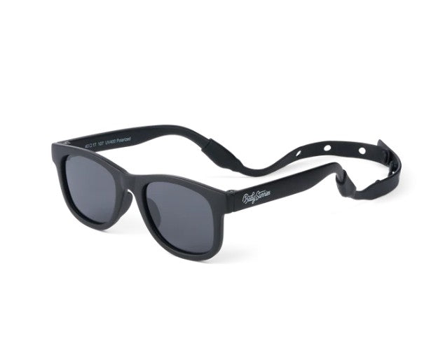 Introducing the Baby Sunnies Black Baby Polarized Sunglasses, designed for ages 0-24 months. These sunglasses feature dark, polarized UV-protective lenses and a black adjustable strap. The arms are printed with writing, and the product is shown against a white background.