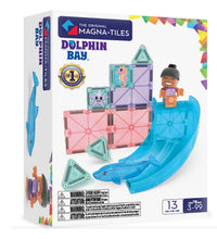 The Magna-Tiles Dolphin Bay 13-Piece Set by Magna-Tiles features ocean-themed magnetic building tiles, including pieces shaped like a dolphin and a pink star, as well as a smiling child figure on a blue slide. Designed for ages 3–99.