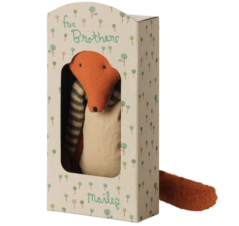 The Maileg Fox, Little brother is a soft orange plush toy by Maileg, dressed in a striped sweater and presented in a decorative box adorned with tree patterns and a window labeled “Fox Brothers Maileg”—an ideal gift to spark imaginative play.